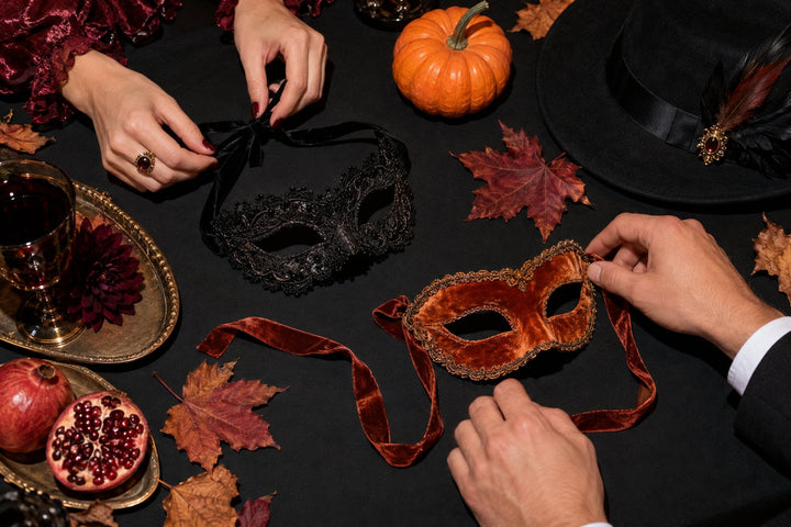 Costume Halloween couple : deux paires de mains nouent des masques en dentelle et en velours sur une table noire