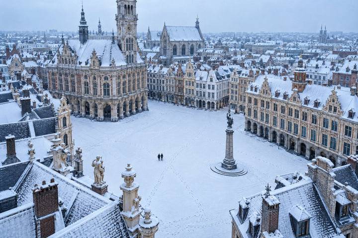 Love room à Lille : vue aérienne de la Grand Place enneigée, un couple laisse ses traces de pas