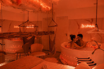 Couple profitant du spa privatif de La Rêverie dans une ambiance lumineuse rouge, chaleureuse et romantique